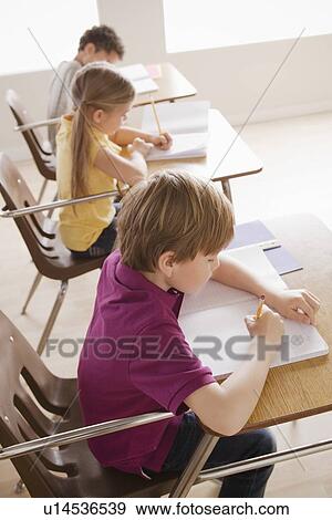 Stock Photo - Schoolchildren focused on writing in classroom. Fotosearch
