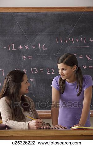 Stock Image - Schoolgirl (12-13) and teacher face to face with blackboard in background. Fotosearch