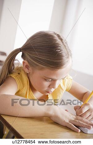 Schoolgirl focused on writing in classroom View Large Photo Image Picture - Schoolgirl focused on writing in classroom. Fotosearch