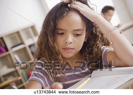 Picture - Schoolgirl focused on writing in classroom. Fotosearch