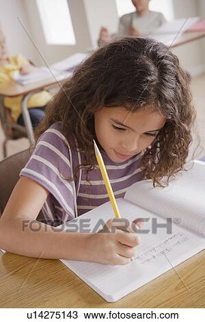 Schoolgirl focused on writing in classroom View Large Photo Image Stock Image - Schoolgirl focused on writing in classroom. Fotosearch