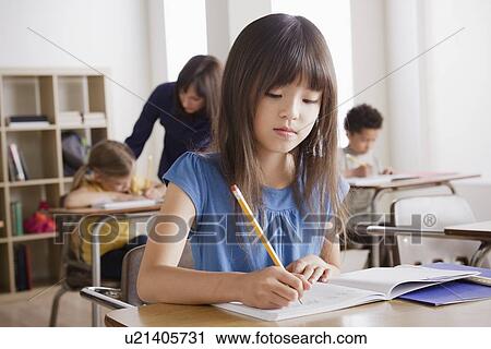 Stock Image - Schoolgirl focused on writing. Fotosearch