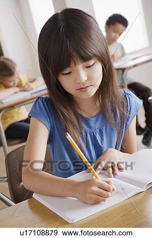 Schoolgirl focused on writing View Large Photo Image Stock Photo - Schoolgirl focused on writing. Fotosearch