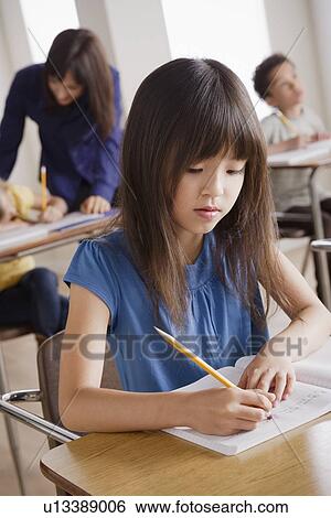Schoolgirl focused on writing View Large Photo Image Stock Photograph - Schoolgirl focused on writing. Fotosearch