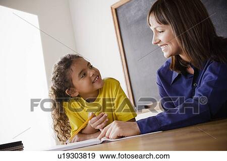 Schoolgirl writing with teacher in classroom View Large Photo Image Stock Photo - Schoolgirl writing with teacher in classroom. Fotosearch
