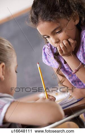 Stock Image - Schoolgirls in classroom. Fotosearch