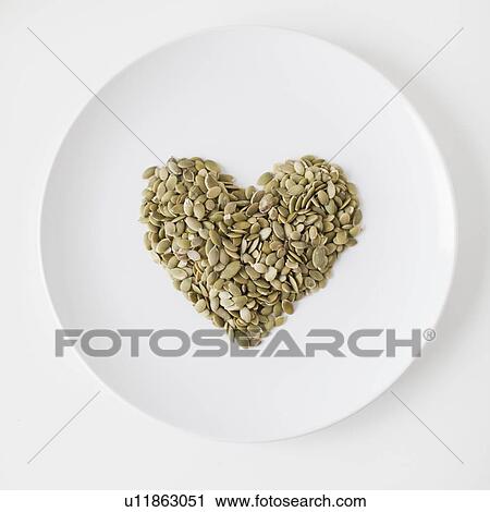 Stock Image - Seeds heart on plate, studio shot. Fotosearch