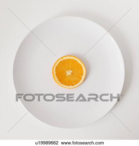 Stock Image - Slice of orange on plate, studio shot. Fotosearch