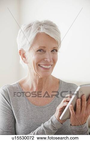 Smiling senior woman using digital tablet View Large Photo Image Stock Image - Smiling senior woman using digital tablet. Fotosearch