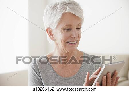 Stock Image - Smiling senior woman using digital tablet. Fotosearch