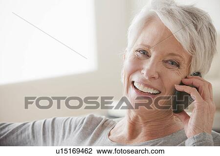 Stock Image - Smiling senior woman using mobile phone. Fotosearch