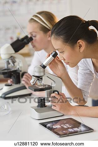 Stock Image - Students (14-17) in chemistry lab using microscope. Fotosearch