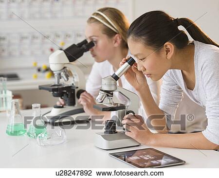 Stock Image - Students (14-17) in chemistry lab using microscope. Fotosearch