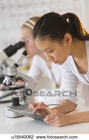 Stock Image - Students (14-17) using tablet pc in chemistry lab. Fotosearch