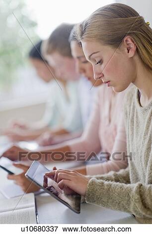 Stock Photo - Students (14-19) using digital tablets in classroom. Fotosearch