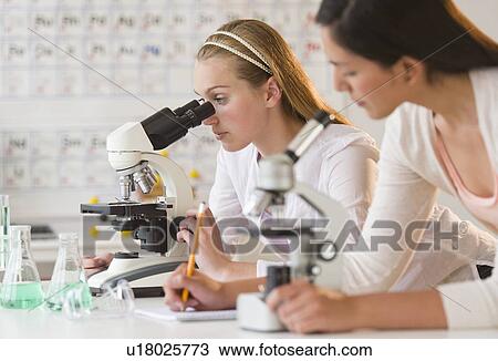 Stock Image - Students (16-19) in chemistry lab using microscope. Fotosearch