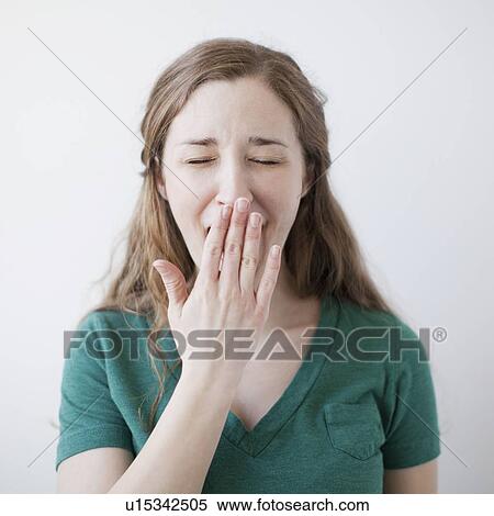 Stock Photography - Studio shot of happy young woman yawning. Fotosearch