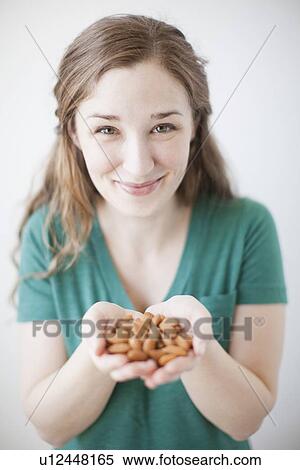 Stock Photography - Studio shot of woman showing handful of almonds. Fotosearch