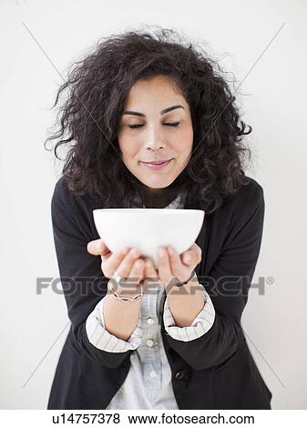 Stock Photo - Studio shot of young woman holding white bowl. Fotosearch
