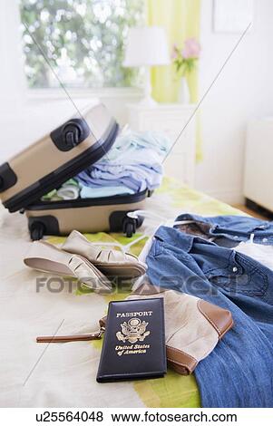 Stock Photo - Suitcase and passport on bed during packing. Fotosearch