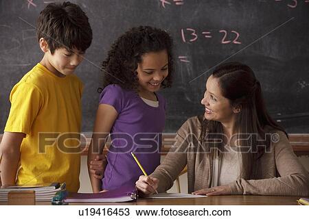 Stock Image - Teacher explaining exercise to schoolgirl (10-11) and schoolboy (12-13). Fotosearch