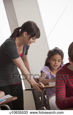 Stock Image - Teacher helping schoolchildren (6-7). Fotosearch