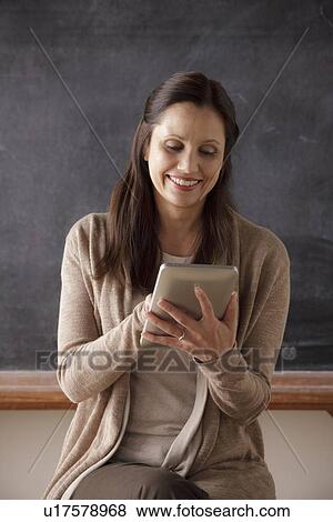 Teacher in classroom holding digital tablet View Large Photo Image Stock Photo - Teacher in classroom holding digital tablet. Fotosearch
