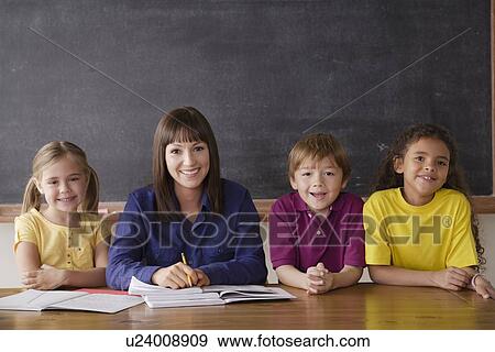 Teacher sitting by desk with group of pupils View Large Photo Image Stock Photo - Teacher sitting by desk with group of pupils. Fotosearch
