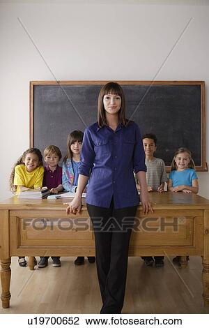 Teacher standing by desk with group of pupils View Large Photo Image Stock Image - Teacher standing by desk with group of pupils. Fotosearch