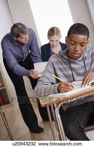 Stock Image - Teacher with teenage students (14-15) at school. Fotosearch