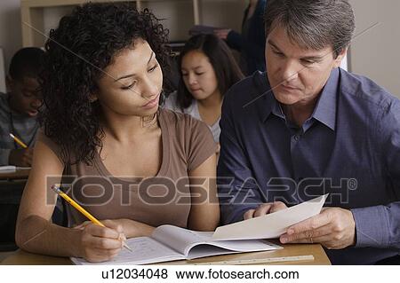 Stock Photo - Teacher with teenage students (14-15, 16-17) at school. Fotosearch