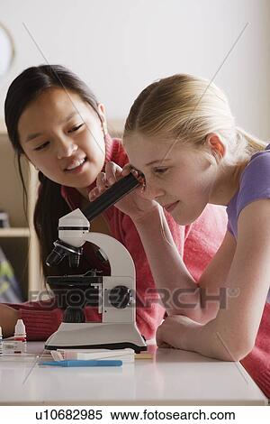 Stock Photography - Teenage girls (14-15) working with microscope. Fotosearch