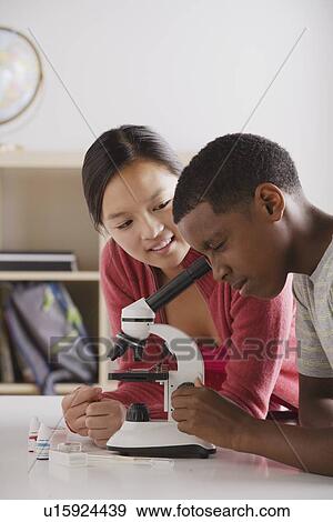Stock Photo - Teenage students (14-15) working with microscope. Fotosearch