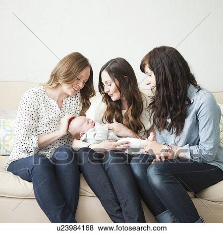 Three young female friends sitting on sofa with baby boy (2-5 months) o0n their lap View Large Photo Image Stock Photo - Three young female friends sitting on sofa with baby boy (2-5 months) o0n their lap. Fotosearch