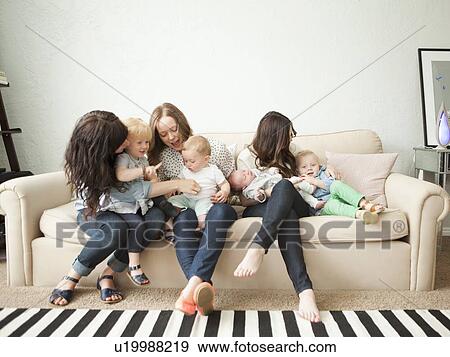 Three young mothers with toddler girl (2-3) and two baby boys (2-5 months, 6-11 months) sitting together on sofa View Large Photo Image Stock Photo - Three young mothers with toddler girl (2-3) and two baby boys (2-5 months, 6-11 months) sitting together on sofa. Fotosearch