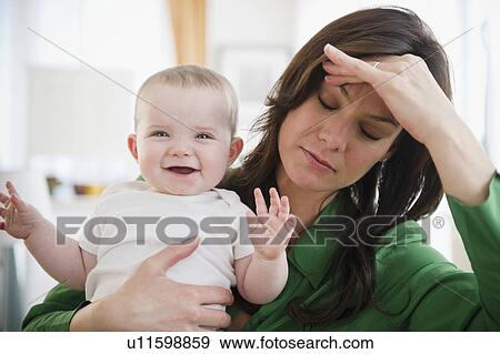 Stock Photo - Tired mother holding baby daughter (6-11 months). Fotosearch