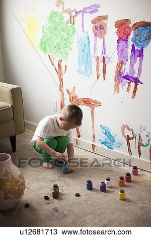 Stock Image - Toddler boy (2-3) painting on wall. Fotosearch