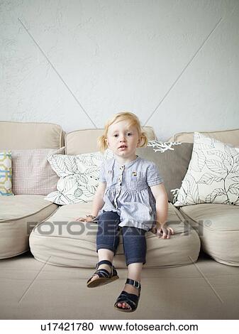 Stock Image - Toddler girl (2-3) sitting on sofa. Fotosearch