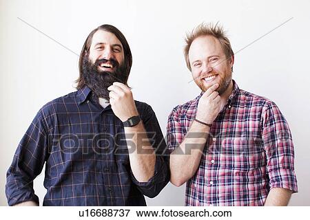 Stock Photo - Two bearded males posing together with hands on chins. Fotosearch