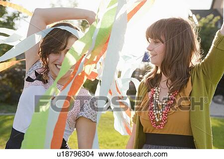 Picture - Two happy female friends playing in domestic garden. Fotosearch