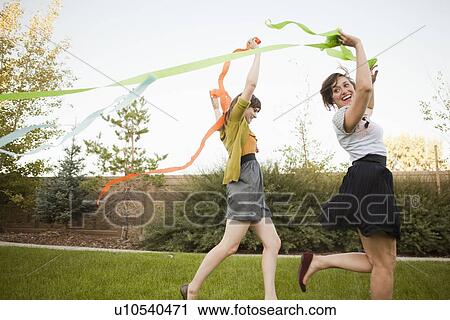 Two happy female friends playing in domestic garden View Large Photo Image Stock Image - Two happy female friends playing in domestic garden. Fotosearch