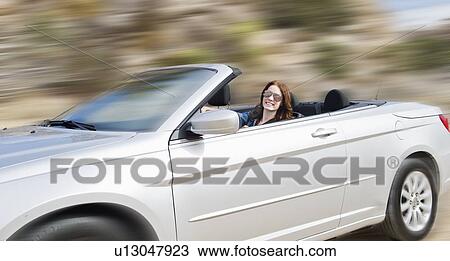 Stock Image - USA, California, Joshua Tree National Park, Young woman driving convertible. Fotosearch