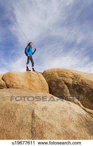 Stock Image - USA, California, Joshua Tree National Park, Female hiker on rocks. Fotosearch