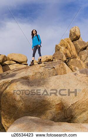 Stock Image - USA, California, Joshua Tree National Park, Female hiker on rocks. Fotosearch