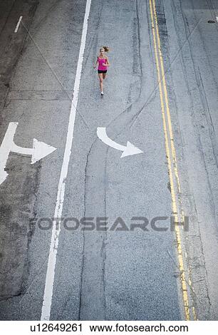 Stock Image - USA, California, Los Angeles, Elevated view of woman running on street. Fotosearch