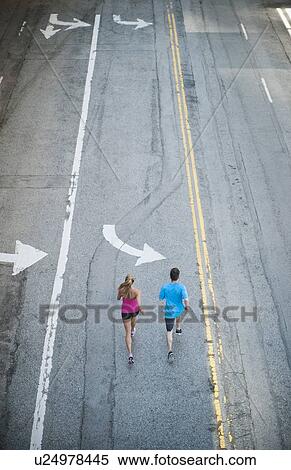 Stock Photography - USA, California, Los Angeles, Elevated view of man and woman running on street. Fotosearch