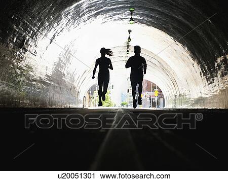 Stock Image - USA, California, Los Angeles, Man and woman running in tunnel. Fotosearch