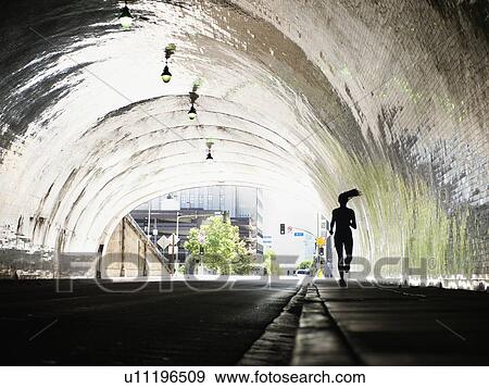 Stock Photo - USA, California, Los Angeles, Woman running in tunnel. Fotosearch