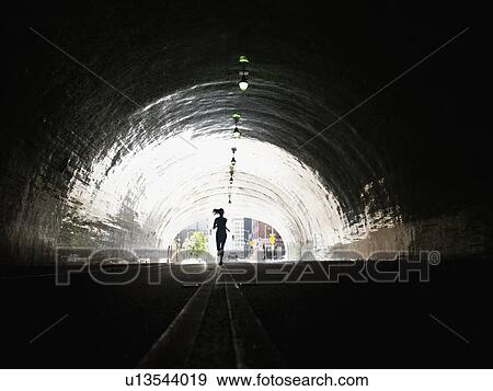 Stock Photo - USA, California, Los Angeles, Woman running in tunnel. Fotosearch