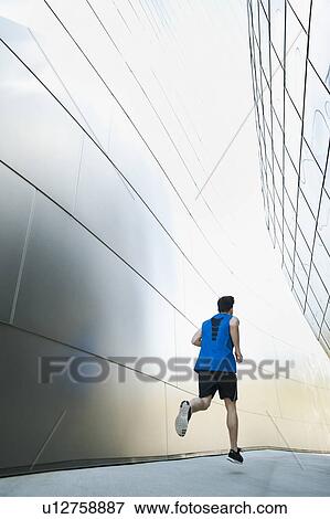 Stock Photo - USA, California, Los Angeles, Young man jogging in city. Fotosearch